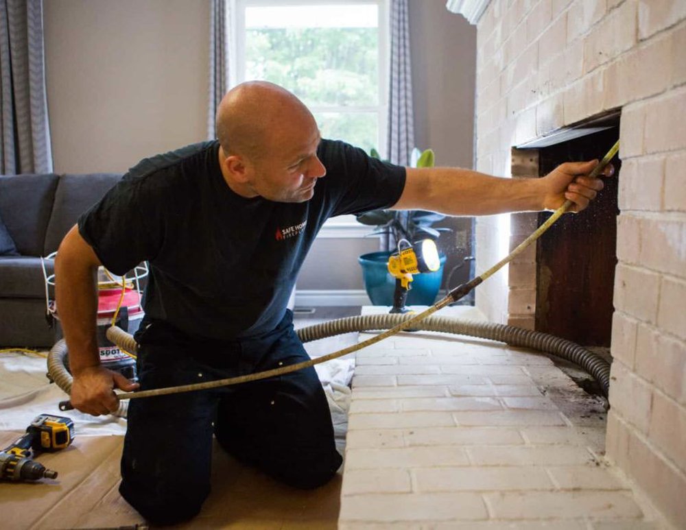 Green Home Services technician sweeping a fireplace and chimney